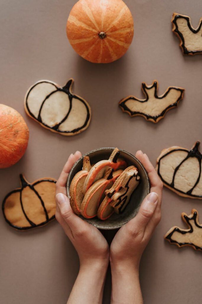 a person holding a bowl of halloween cookies